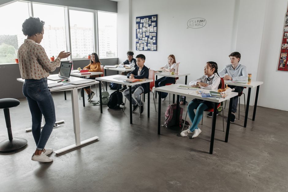 Teacher interacting with students in a modern classroom, fostering a diverse and engaging educational environment.