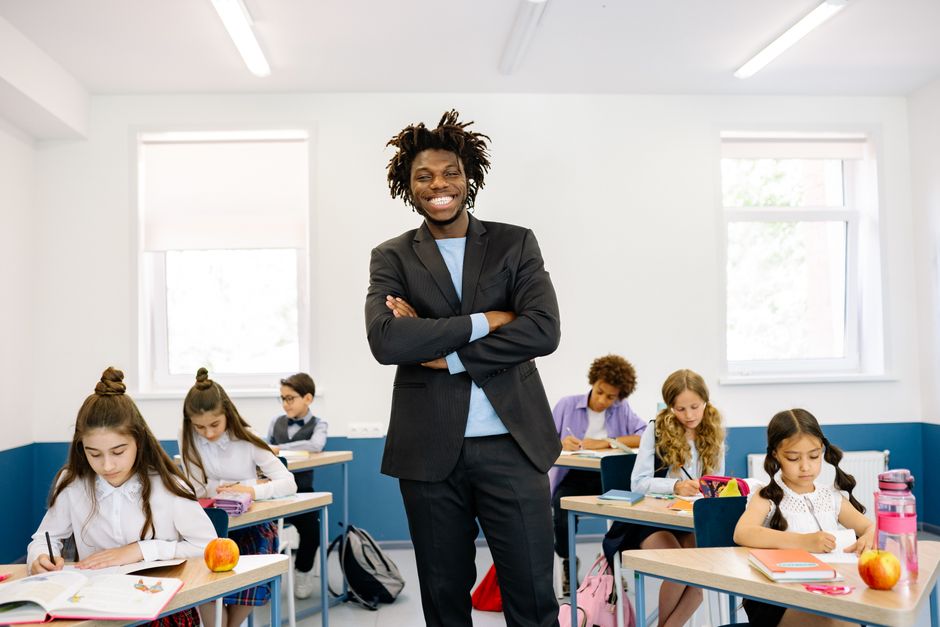 Smiling teacher standing in diverse classroom