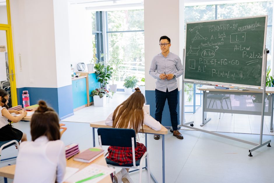 Teacher instructing students in a bright classroom with math equations