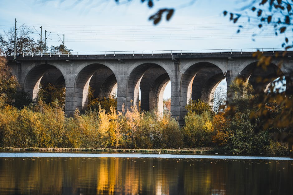 Majestic railway bridge in Bielefeld with vibrant autumn foliage and river reflections